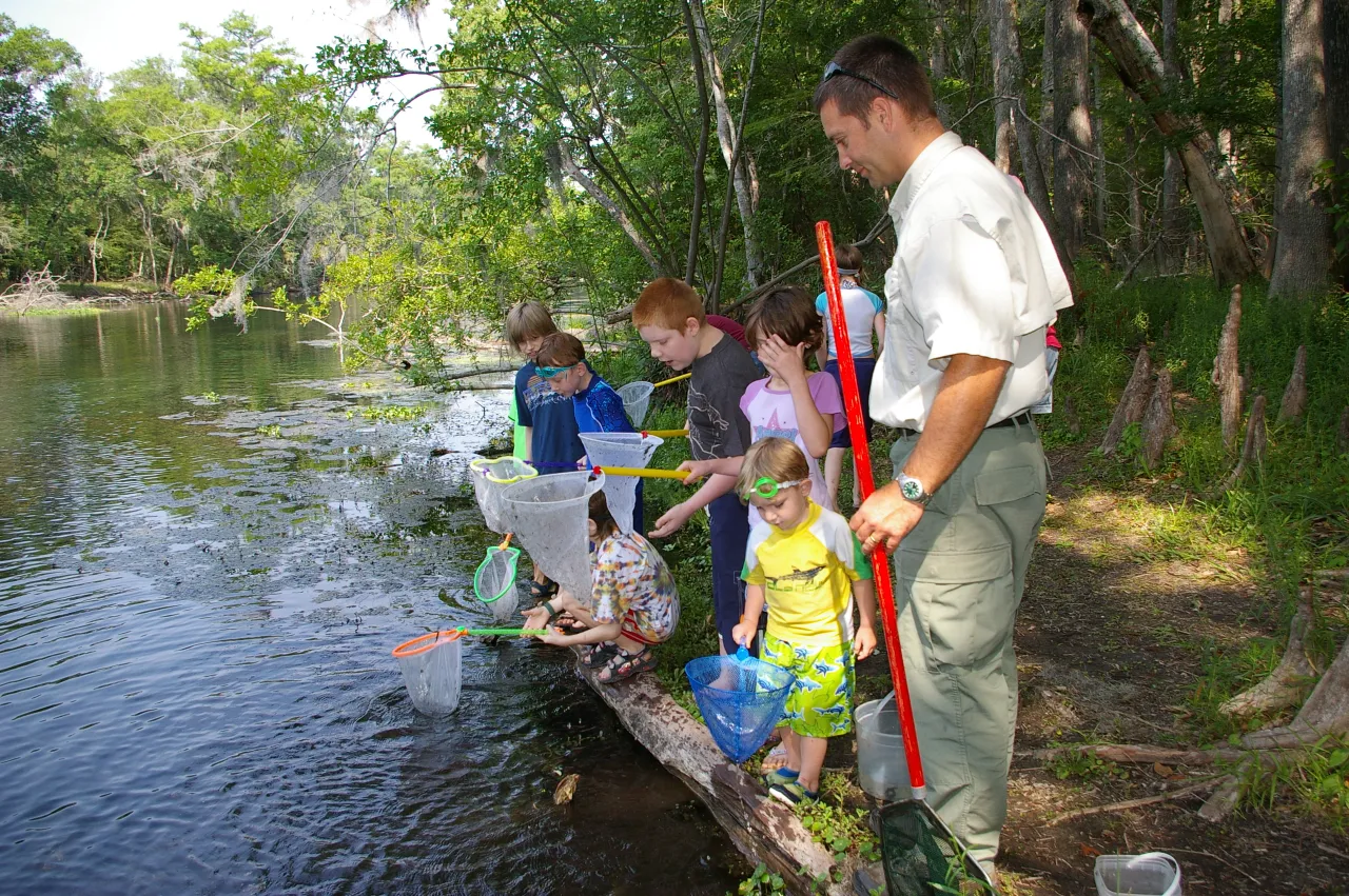 Children sampling water with a scientist